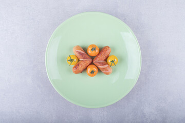 Fried sausages and cherry tomatoes on green plate