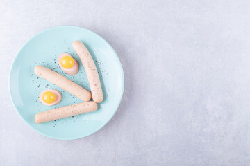 Boiled sausages and egg yolk on blue plate