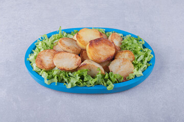 Fried potatoes and lettuce on blue plate