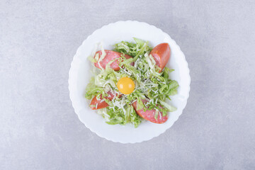 Sliced smoked sausages, lettuce and egg yolk in white bowl