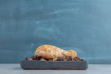 A wooden board with fried chicken leg meat and eggplants