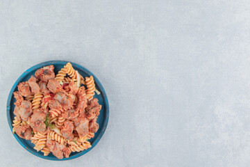 A wooden plate of spiral pasta with herbs