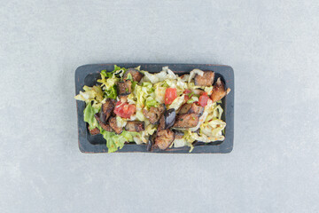A wooden board with vegetable salad and fried eggplant