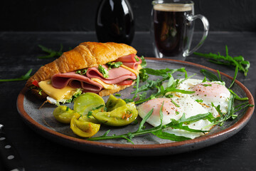 Breakfast with fried eggs and croissant sandwith with ham, cheese and salad. Delicious morning breakfast