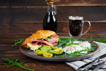 Breakfast with fried eggs and croissant sandwith with ham, cheese and salad. Delicious morning breakfast