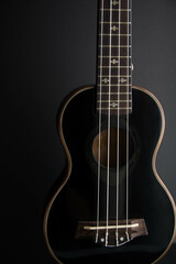 Fototapeta na wymiar Close up ukulele isolated on dark background. Copy text.