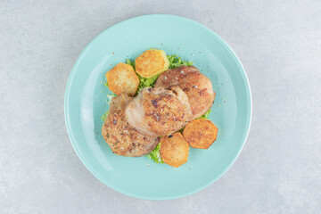 A blue plate of meat with fried sliced potatoes and lettuce