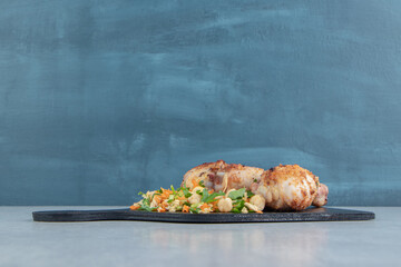 A wooden board with fried chicken legs and vegetable salad