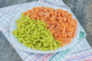 Hearth shaped pasta with fusilli pasta in plate, on the towel , on the marble background