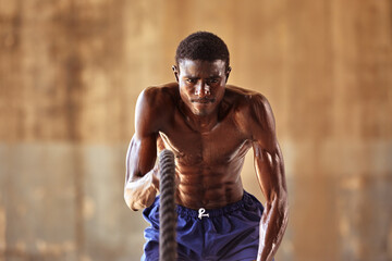 Rope workout. Sport man doing battle ropes exercise outdoor. Black male athlete exercising, doing...
