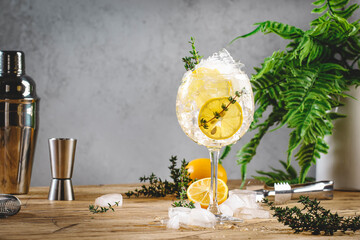 Gin tonic lemon cocktail drink with dry gin, bitter tonic, juice, thyme and ice, bar tools. Wooden table background with copy space - obrazy, fototapety, plakaty