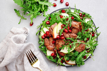 Healthy fresh salad with chicken liver, apple, pomegranate and arugula. White kitchen table background, top view