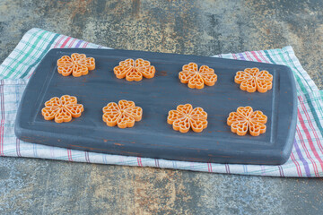 Flowers made from macaroni on board, on the towel, on the marble background