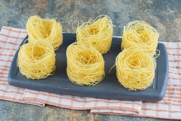Six stacks of thin spaghettis in the board ,on towel, on the marble background