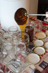 Filling of glass jars of honey on a table