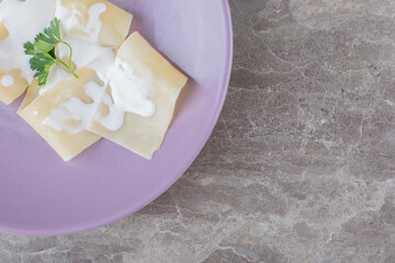 Yogurt on lasagna sheets with greens on the plate, on the marble background