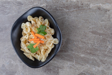 Traditional Italian pasta with finely chopped carrot and green vegetable, on the marble background