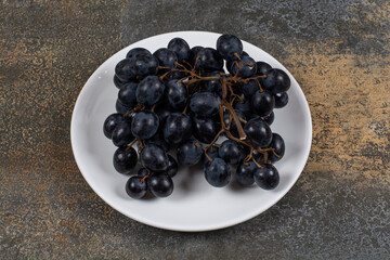 Cluster of black grapes on white plate