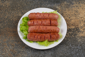 Roasted tasty sausages with lettuce on white plate