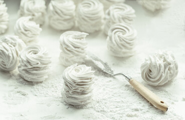 Homemade apple white marshmallows on a white background. Homemade healthy meringue cakes on a parchment sprinkled with powdered sugar