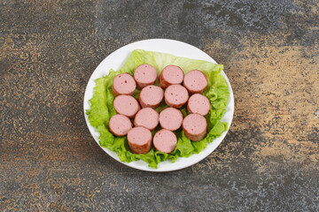 Grilled sliced sausages and lettuce on white plate