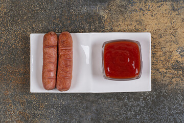 Fried sausages and ketchup on white plate