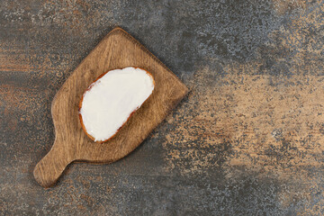 Slice of toast with sour cream on wooden board