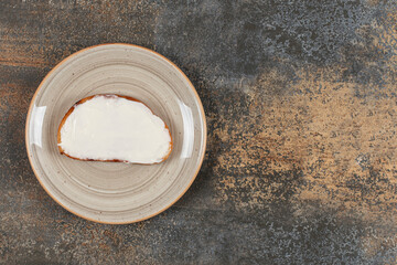 Slice of toast with sour cream on ceramic plate