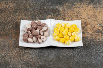 Tasty brown and yellow candies in blue bowl