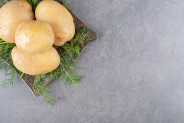 A black board of uncooked potatoes with fresh dill