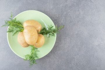 A green plate of uncooked potatoes with fresh dill