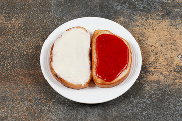 Toasts with strawberry jam and sour cream on white plate