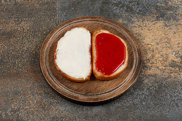 Toasts with strawberry jam and sour cream on wooden board