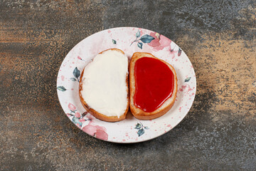 Toasts with strawberry jam and sour cream on colorful plate