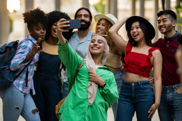 Tourists taking selfie in the city, multiracial diverse friends. - focus on muslim woman with...