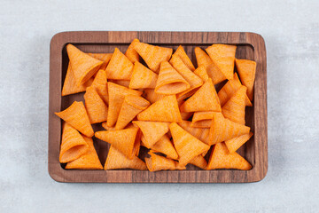 Delicious crunchy chips on wooden plate