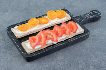 Crispy toasts with tomatoes on wooden board