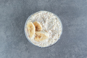 A glass plate of oatmeal porridge with slices of banana