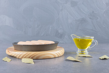 A black plate of boiled sausages with oil