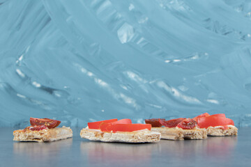 Crispy toasts with tomatoes on marble background
