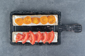 Crispy toasts with tomatoes on wooden board