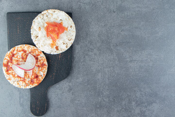 Crispy puffed rice toasts with tomatoes on wooden board