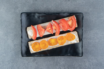 Crispy toasts with tomatoes on black plate