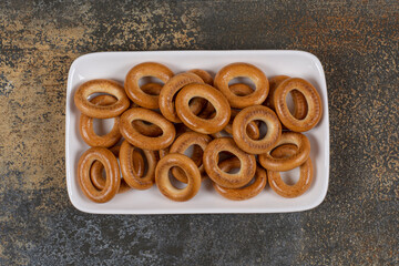 Plate of tasty crackers on marble background