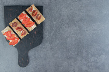 Obraz premium A black wooden board of crispy toasts with tomatoes