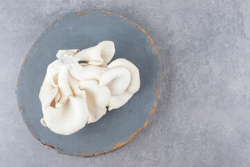 A wooden board with white mushrooms