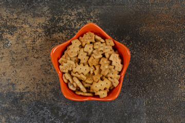 Orange bowl of crackers on marble background