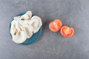 A wooden plate with mushrooms and sliced tomato