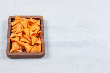 Delicious crunchy chips on wooden plate