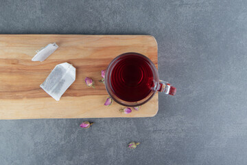A glass cup of rosehip tea on a wooden board